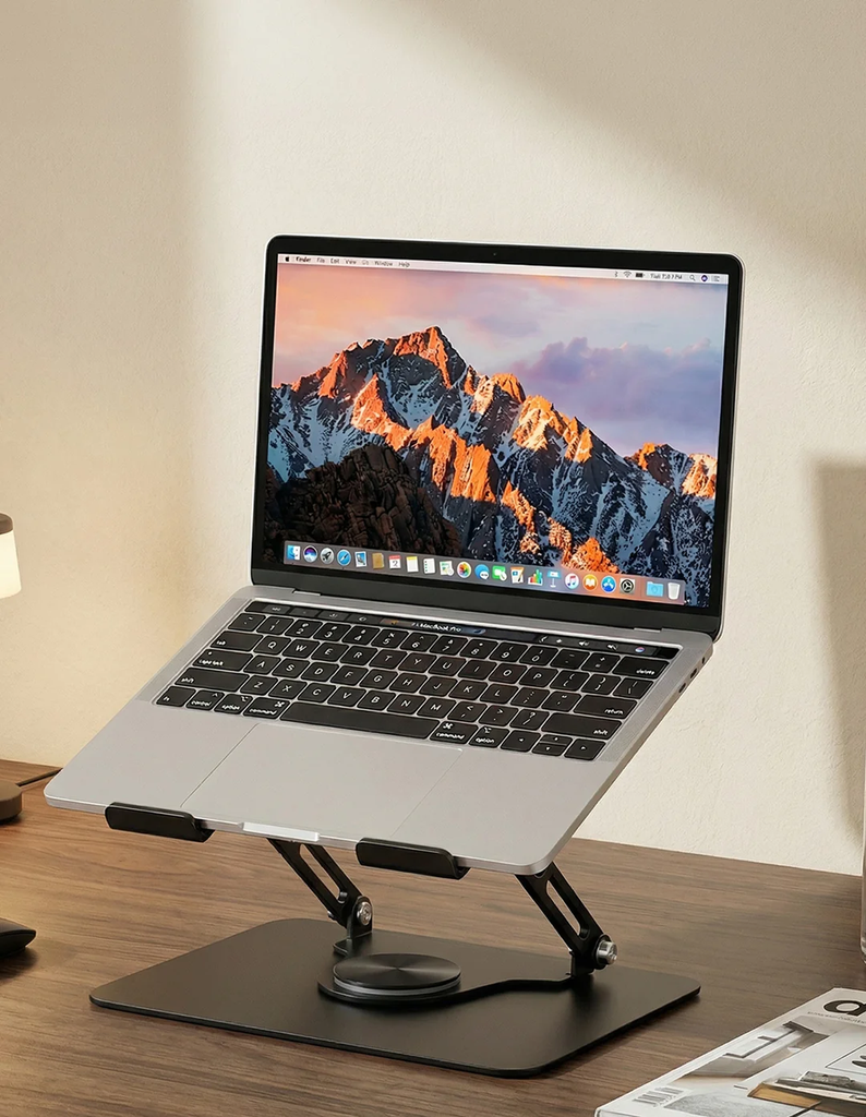Silver laptop on a stand showing a mountain landscape on its screen